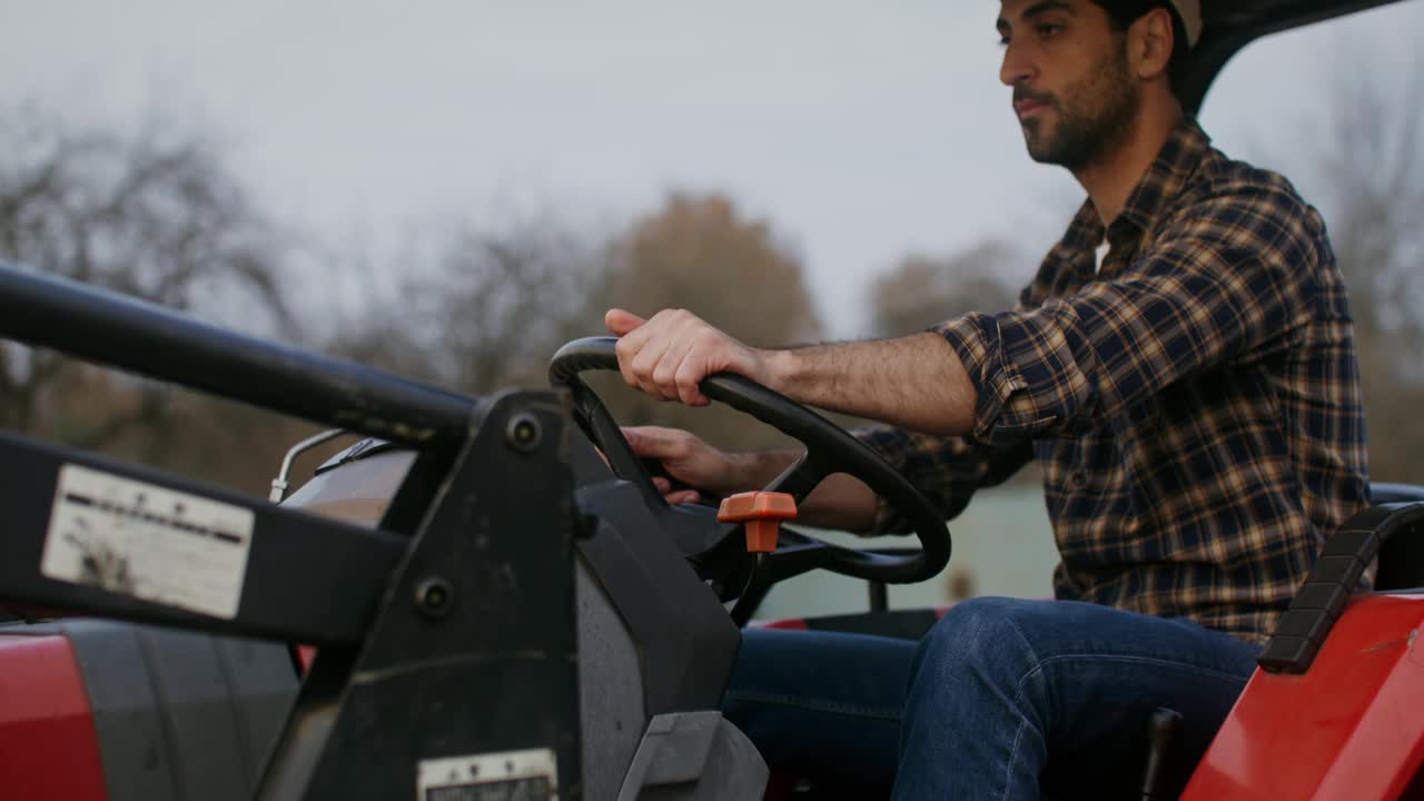 一个年轻的农民骑着拖拉机四处察看，检查他的财产