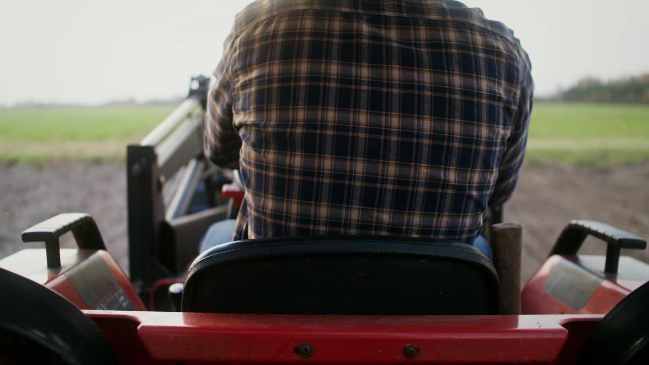 一个拖拉机司机坐在一个机器的车轮上的特写后视图
