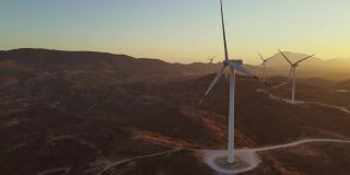 日出时的风力涡轮机。风力发电厂产生绿色能源与碳中性