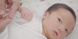快乐的亚洲家庭母亲打扮新生婴儿(0-1个月)男婴。