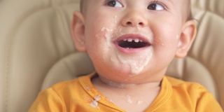 12-18个月大的蹒跚学步的孩子吃麦片粥时，会翻盘子。吃东西的时候又脏又搞笑的娃娃脸