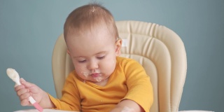 12-18个月大的幼儿吃麦片粥，用手在桌子上移动盘子。这孩子放纵地玩食物