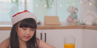 亚洲小孩在家与父母一起享受圣诞派对。有吸引力的漂亮夫妇在餐桌上为年轻的女儿提供晚餐，庆祝圣诞晚会在家里。