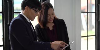 亚洲商人和女商人在办公室开会时使用平板电脑进行讨论。两名工人谈话和培训工作。团队合作的建议