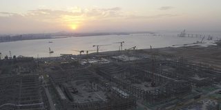 日落时分，一座大型城市建筑群的施工现场，天空中浪漫的彩云