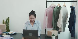一位亚洲企业家正在准备她的衣服，这些衣服可以装在纸盒里卖给顾客。