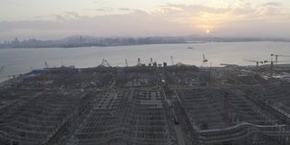 日落时分，一座大型城市建筑群的施工现场，天空中浪漫的彩云