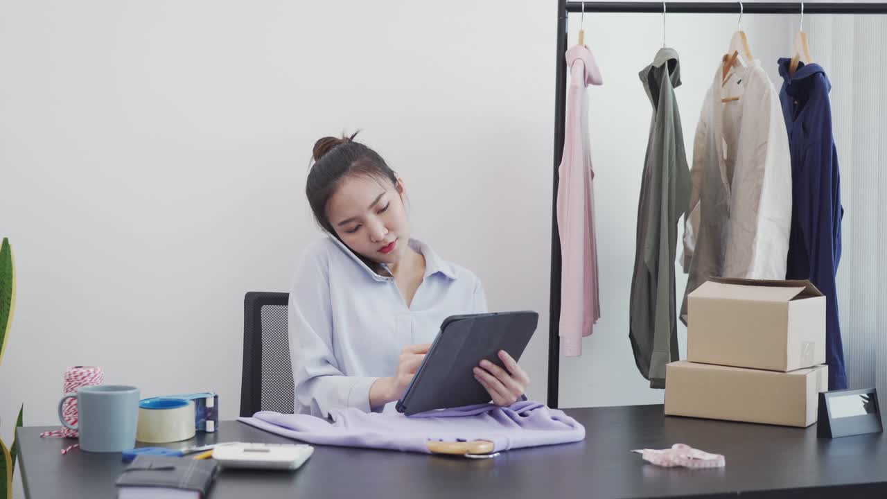 亚洲企业家一边在平板电脑上查看库存，一边与客户通电话。