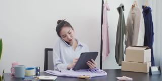 亚洲企业家一边在平板电脑上查看库存，一边与客户通电话。