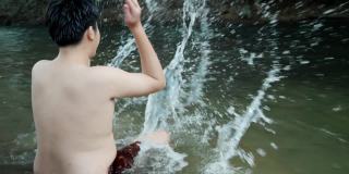 快乐亚洲男孩在河里戏水，户外生活理念。