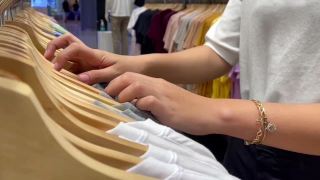女人用手整理了许多衣架上的服装。在商店挑选和购买衣服。购物视频素材模板下载