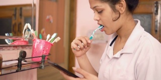 印度一名年轻女子一边刷牙一边看手机。