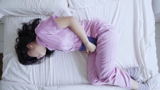 生病的妇女在床上压胃视频素材模板下载