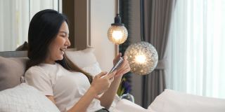 早上在床上用智能手机查看社交应用的亚洲女性。