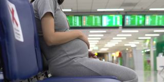 快乐的孕妇在机场使用手机