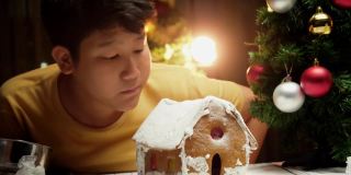 亚洲男孩看着DIY姜饼屋完成后，圣诞节庆祝的生活理念。
