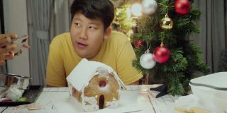 亚洲男孩看着DIY姜饼屋完成后，圣诞节庆祝的生活理念。