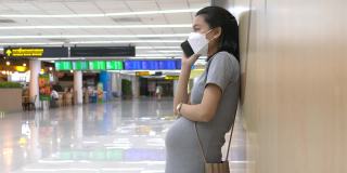 快乐的孕妇在机场使用手机