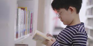 亚洲男孩在图书馆的书架上寻找书籍。