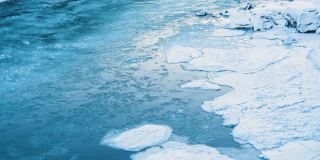 冰冻的河流，寒冷的冬天或春天的景观，一条有着巨大水流的冰冻河流，冰块沿着河流漂流。清澈的水和冰，冰岛一条正在融化的冰川河