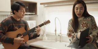 年轻夫妇在厨房里一起唱歌玩得很开心。