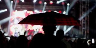 快乐的人们在雨中撑着雨伞观看一场精彩的音乐会