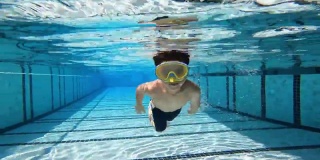 一个亚洲男孩在游泳池的水下玩耍和游泳