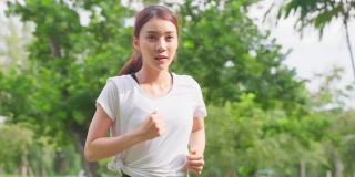 亚洲年轻美丽的运动女子在公园的街道上跑步。美丽的运动员和坚定的女孩在运动服装锻炼慢跑锻炼户外保健在傍晚日落在花园。