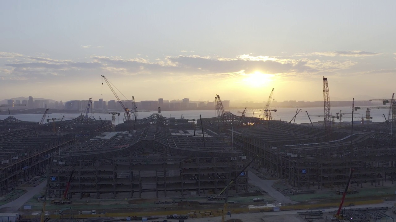 日落时分，一座大型城市建筑群的施工现场，天空中浪漫的彩云