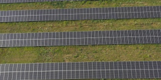 空中拍摄一排排安装在草地上发电的太阳能电池板。从太阳能中获取清洁、环保的能源。现代可再生绿色能源概念。俯视图
