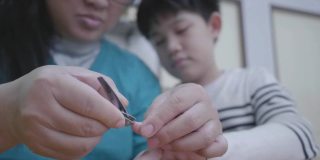 亚洲母亲在家里剪她儿子的指甲