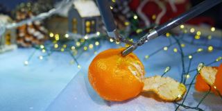 人形机器人在为圣诞节做准备时剥橘子皮。裁剪的观点。计算机的概念