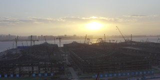 一个大型建筑工地在日落前的背光航拍视频，一个巨大的太阳在天空中