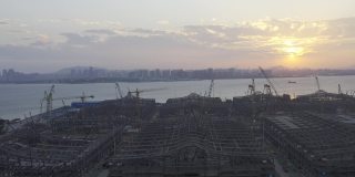 一个大型建筑工地在日落前的背光航拍视频，一个巨大的太阳在天空中