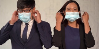 办公室里，一群快乐的亚洲商务人士脱下防护口罩，微笑着迎接新冠肺炎或新冠肺炎大流行的结束。摘掉医用口罩。希望在一个新的正常的人