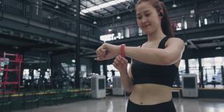 年轻的女运动员在健身房用智能手机听音乐。