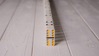 白色多米诺骨牌骰子与彩色点落在一个轻木制背景。视频素材模板下载