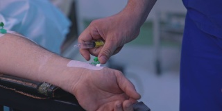 医生将药物注射到病人的手上。男性助理在手术中为病人注射液体。医生在诊所用注射器加药药物。