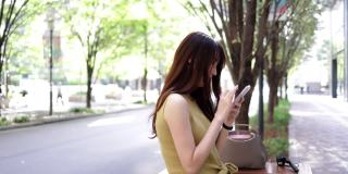 穿着黄色衣服的漂亮女人在城市里使用智能手机