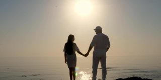 海上的黎明。一对夫妇的剪影，爸爸和女儿在海上欣赏日出。夏天的早晨