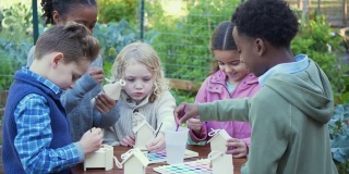 多种族儿童在社区花园画鸟屋
