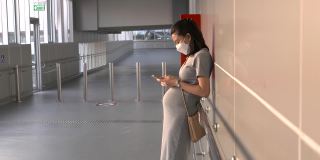 亚洲孕妇戴着口罩等待空中列车，新常态