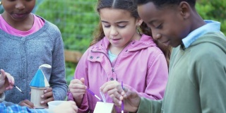 多种族儿童在社区花园画鸟屋