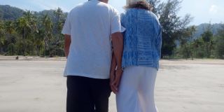 亚洲老年夫妇一起散步在海边的背景周末假期。老年人快乐生活的概念。