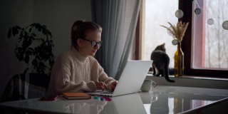 一个年轻女孩在家里工作或学习的时候在笔记本电脑上打字