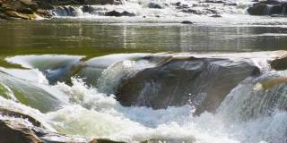 山间河流，清澈的绿松石水瀑布般从湿卵石间倾泻而下，泛着厚厚的白色泡沫