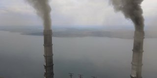 从空中俯瞰燃煤电厂高高的管道，黑烟在污染的大气中向上移动。