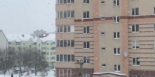 下雪了。模糊的背景，在住宅建筑的背景下飘落的大片雪花。丰富的雪花。从公寓看到的景色