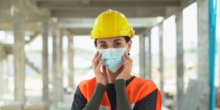 2019冠状病毒病(Covid - 19)大流行期间，建筑工地女工戴着防护口罩的户外照片。工程师戴上医用口罩防止空气污染。慢动作