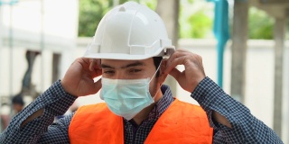 在新冠肺炎或Covid - 19大流行期间，建筑工地工人戴着防护口罩的照片。工程师戴着医用口罩防止空气污染。慢动作